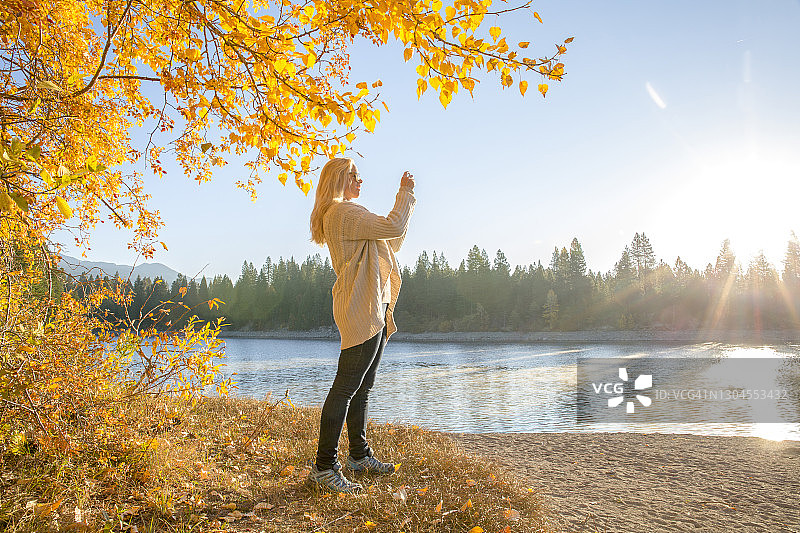 女人拍摄森林和湖泊上的日出图片素材