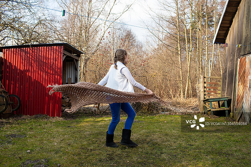 在乡村房屋后院编着辫子，欢快地迎接春天的女孩图片素材