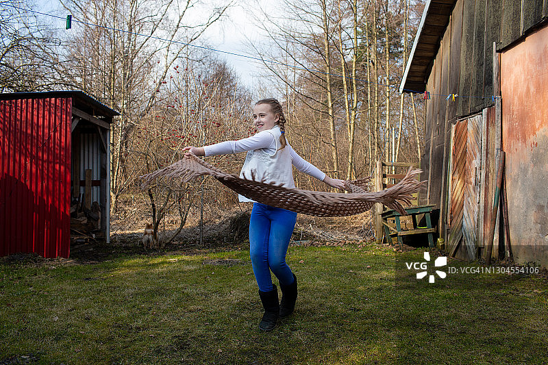 在乡村房屋后院编着辫子，欢快地迎接春天的女孩图片素材