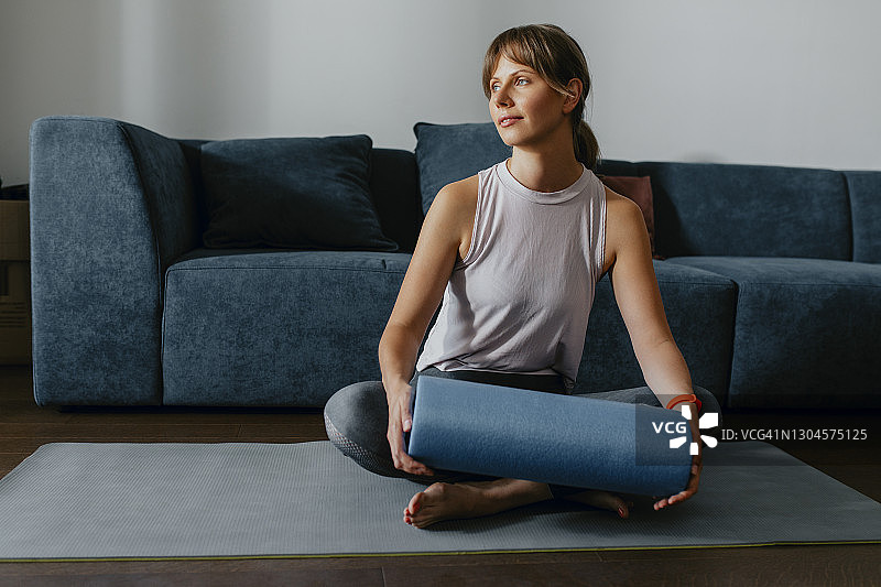 居家锻炼：身穿运动服的女子使用泡沫轴图片素材