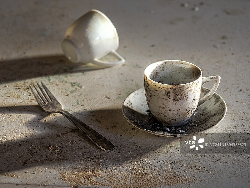 废弃房屋桌子上布满灰尘的脏咖啡杯和叉子图片素材