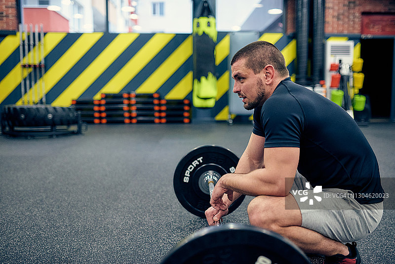 疲惫的男人在健身俱乐部举重图片素材
