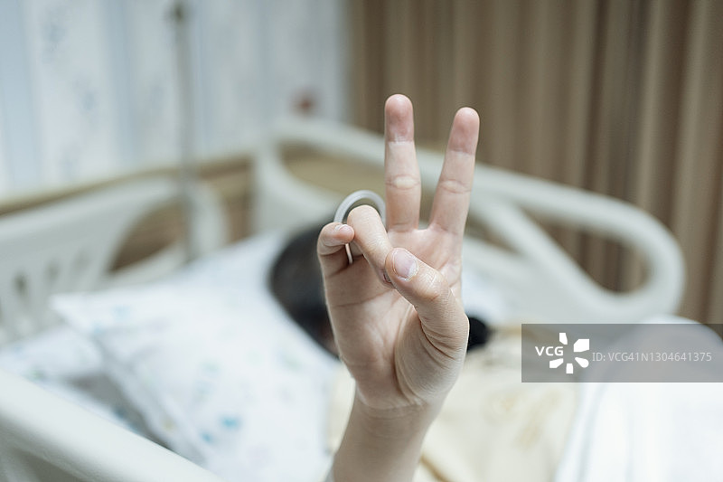 病人输液时手部特写，展示胜利手势图片素材