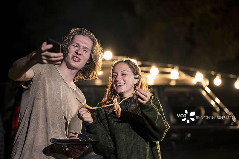 情侣在海鲜烧烤时用智能手机自拍，房车生活，露营生活图片素材