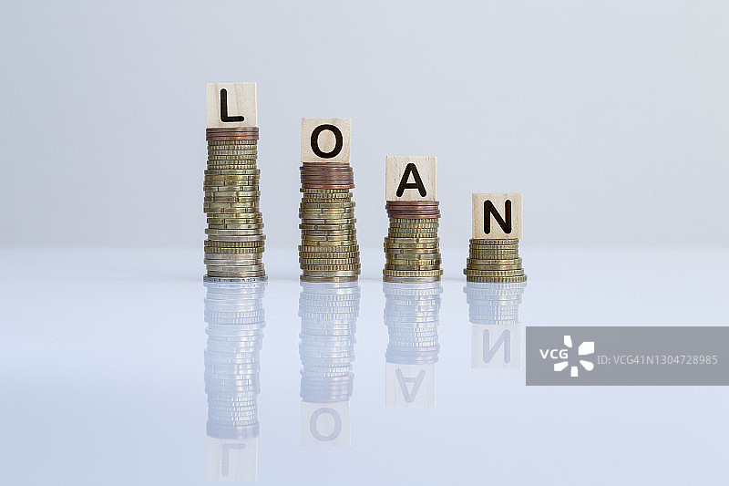 灰色背景上硬币堆叠之上的木块文字“LOAN”图片素材