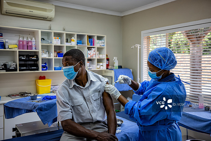 黑色非洲女医生给男病人注射新冠疫苗图片素材