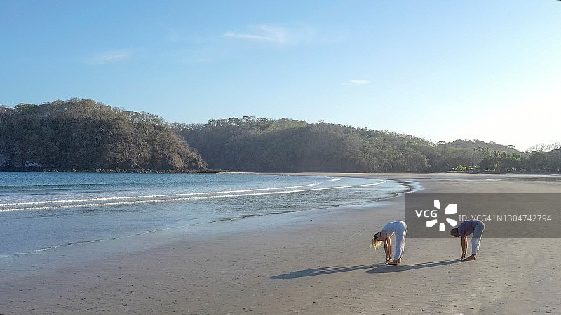 情侣在清晨的沙滩上做瑜伽图片素材