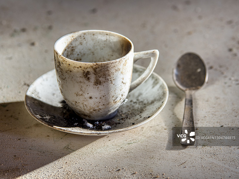 废弃房屋桌子上脏污的布满灰尘的咖啡杯和茶匙图片素材
