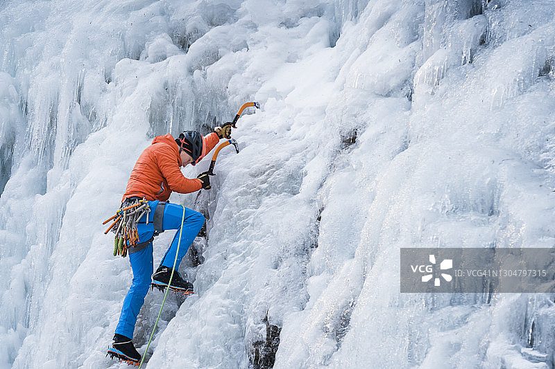 一名男性攀冰者用冰镐和冰爪攀登陡峭的冰墙图片素材