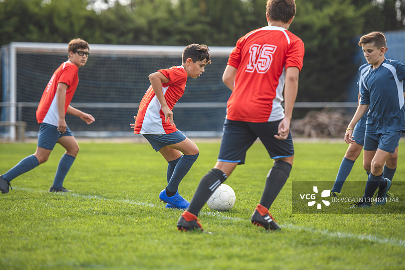 练习赛中控制球的红色球衣足球运动员图片素材