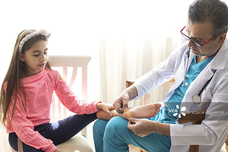 医生用手给受伤的腿贴上膏药图片素材