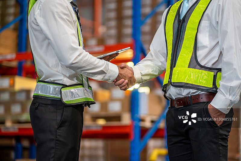 仓库管理人员和员工在工作结束后握手图片素材