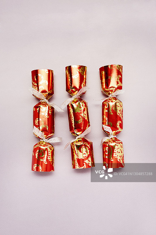 紫色背景上的红色和金色圣诞拉炮俯视照片图片素材