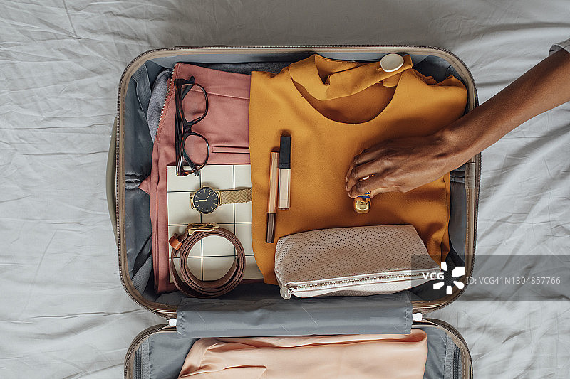 女子将衣服打包到行李箱里图片素材