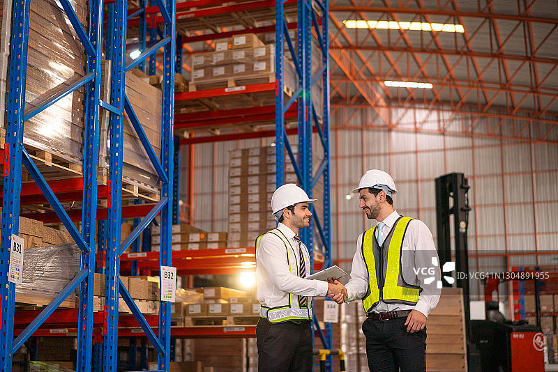 两名头戴头盔的商人在仓库里庆祝商业上的好消息图片素材