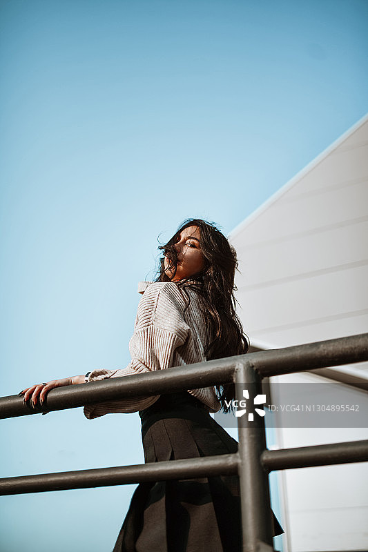 扶着栏杆，享受凉风吹拂秀发的漂亮女人图片素材