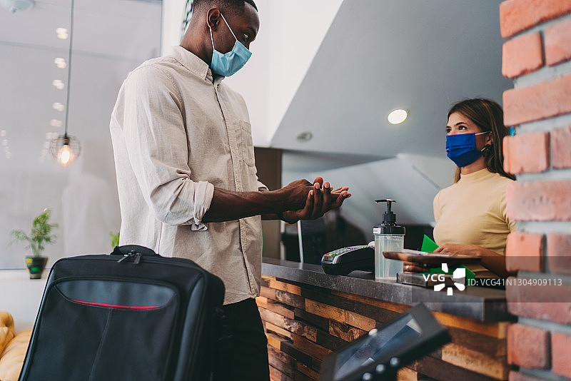新冠疫情期间，游客在酒店前台消毒双手图片素材
