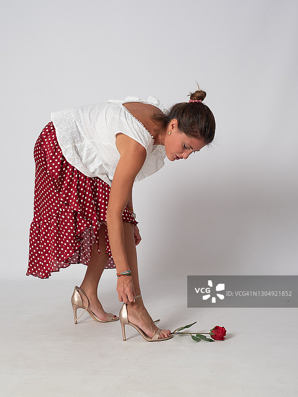 金发女人穿着弗拉门戈服装跳舞并闻着红玫瑰图片素材