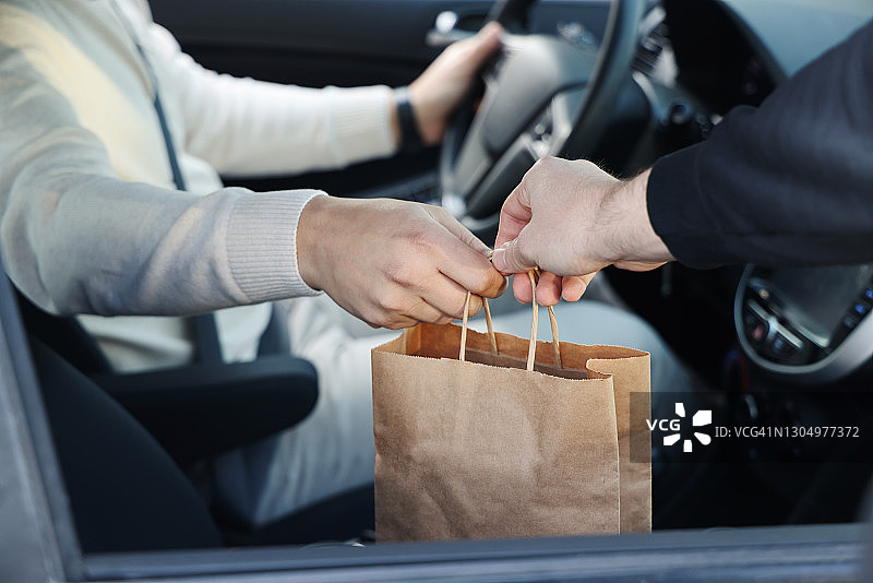 年轻男子从她的车里取外卖食物图片素材