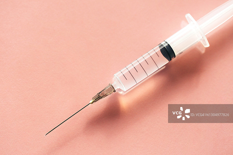 粉色背景上的注射器俯视特写：新冠病毒防护概念图片素材