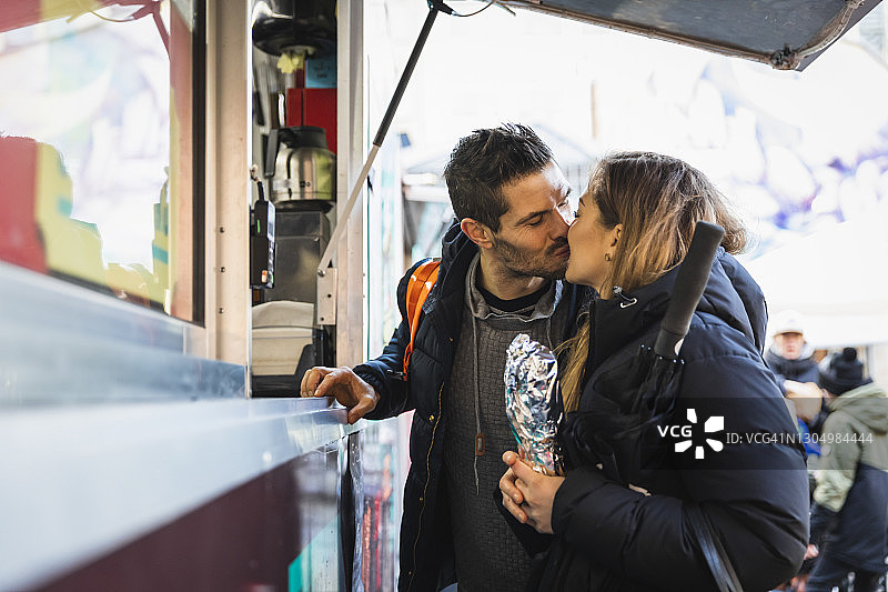 异性情侣在路边咖啡馆购买外卖时亲吻图片素材