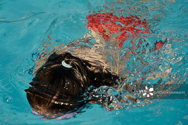 小女孩在泳池里游泳图片素材