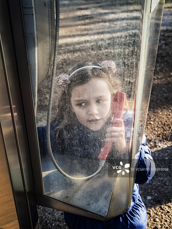 女孩站在电话亭里拿着听筒图片素材