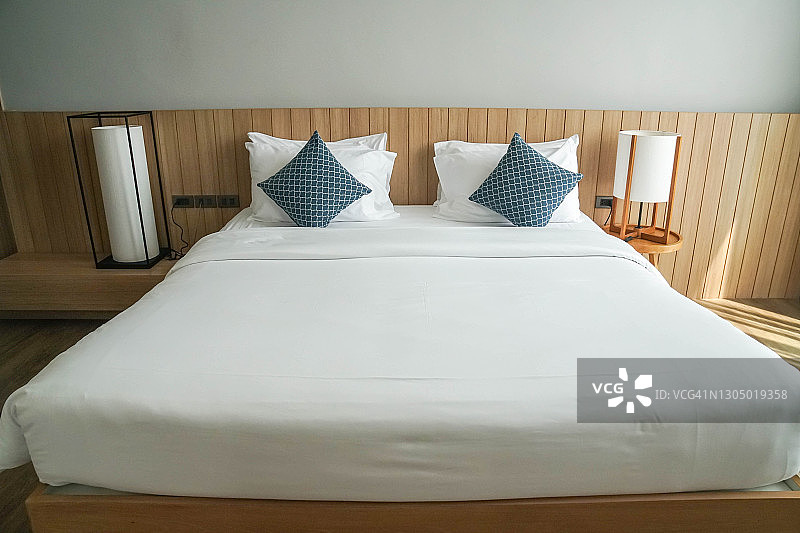 酒店卧室床头柜配长灯的简约双人床白色床垫特写图片素材