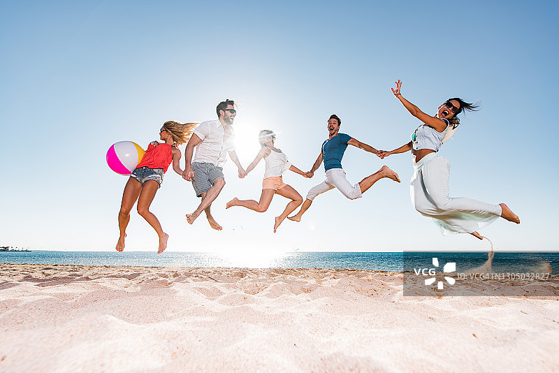 夏日海滩上无忧无虑的朋友们跳跃图片素材