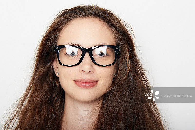 戴着书呆子或潮人眼镜，快乐地看着镜头的年轻女子图片素材