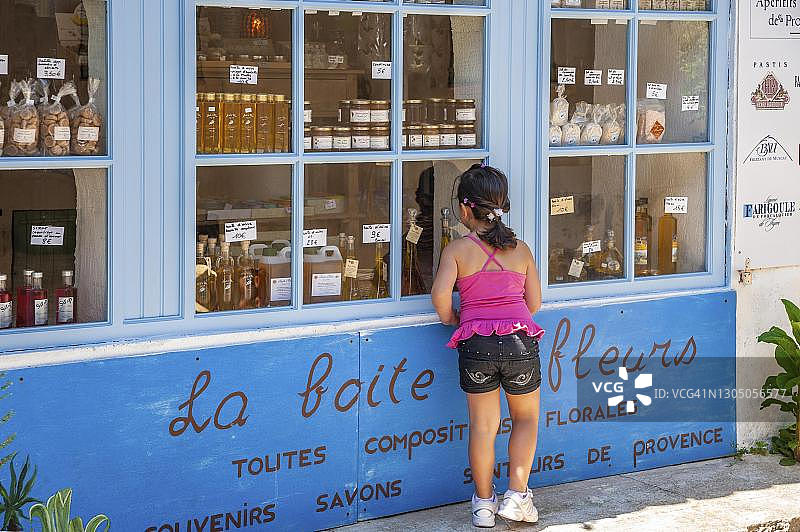 在纪念品商店橱窗前的女孩，法国普罗旺斯-阿尔卑斯-蓝色海岸瓦尔省拉马图埃勒图片素材