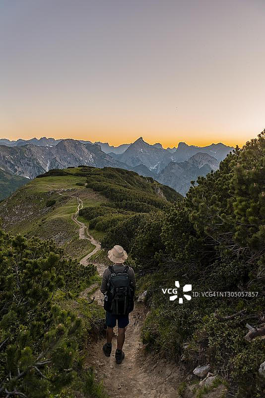 在奥地利卡文德尔山脉拜伦科普夫徒步小径上欣赏落日的旅行者图片素材