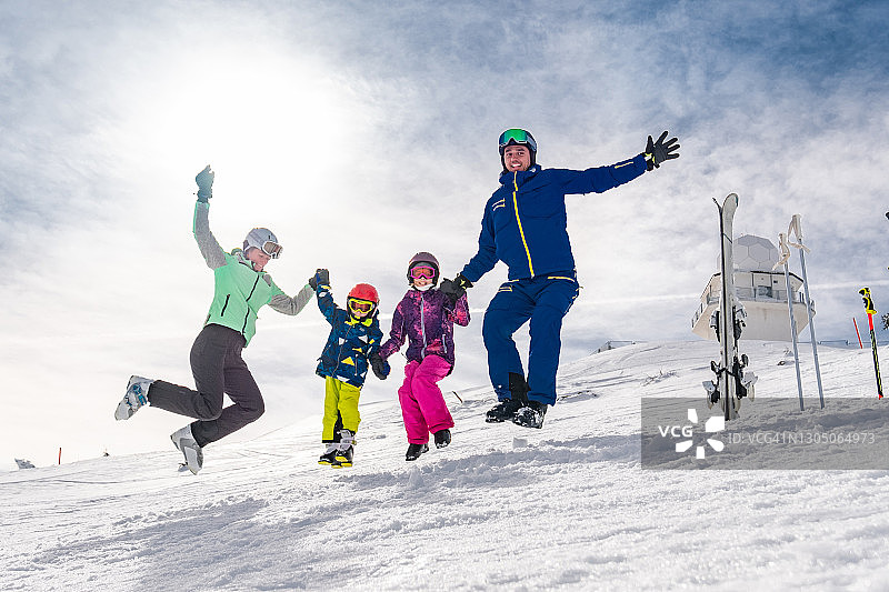 快乐的滑雪家庭在雪地上跳跃玩耍图片素材