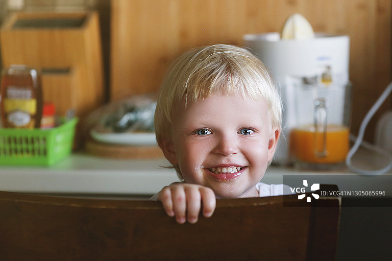 好奇的金发男孩在厨房寻找新鲜橙汁图片素材