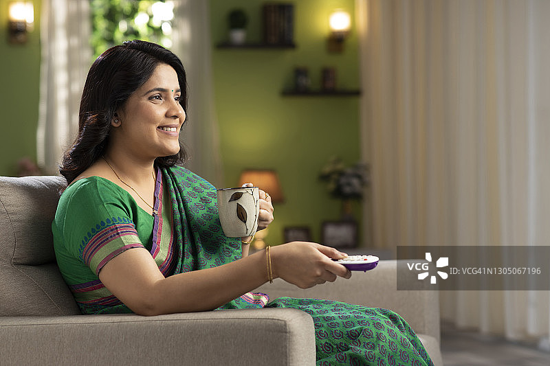 中年妇女在家看电视喝咖啡图片素材