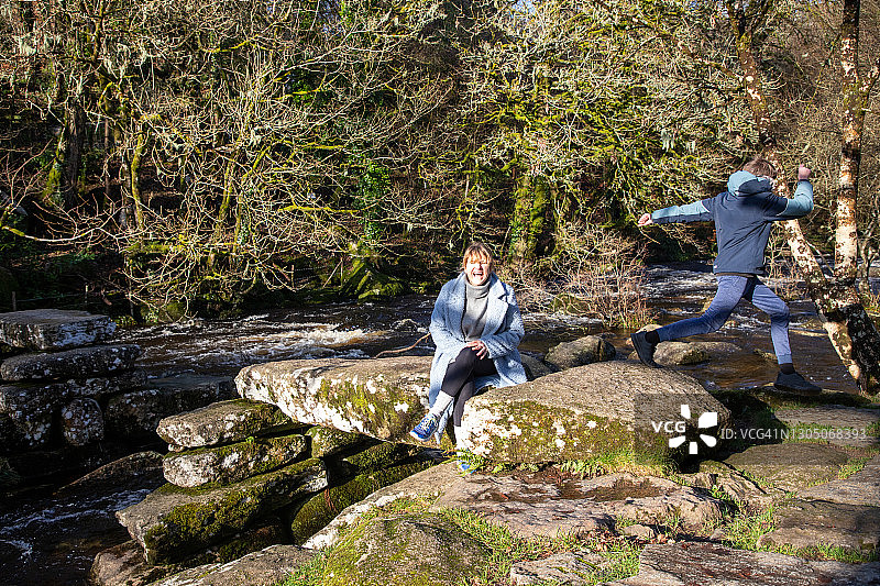 女士坐在岩石上，男孩跑过图片素材