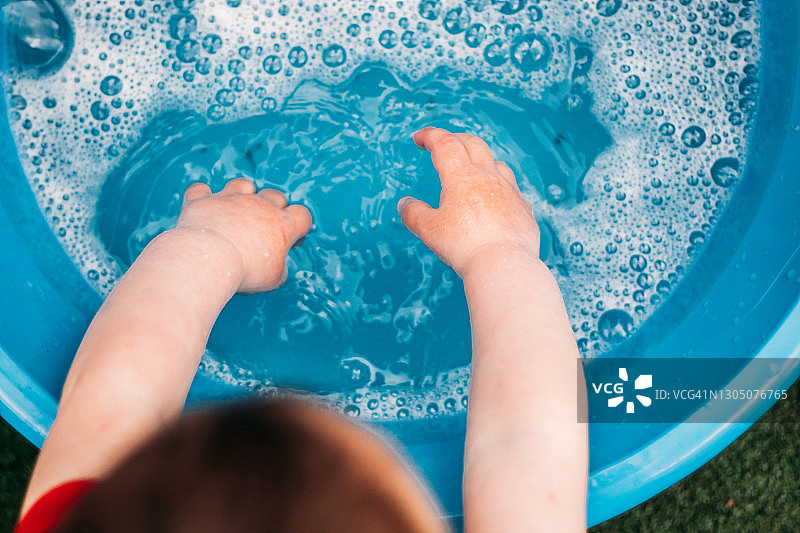 幼儿在蓝色塑料盆上洗手图片素材
