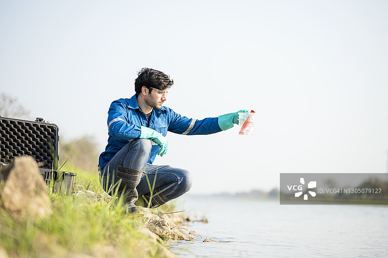 检查受污染废物的白色安全服科学家，检查水并收集水样（pH值）的环境科学家图片素材