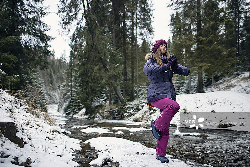 冬季少女在溪流中做平衡练习图片素材