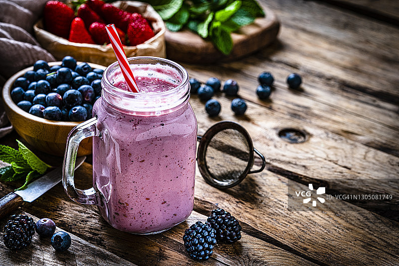 乡村木桌上的混合浆果冰沙图片素材