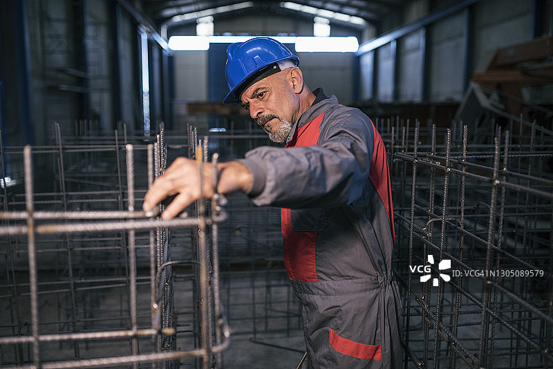 50-60岁的工人在混凝土结构工厂检查钢筋结构图片素材