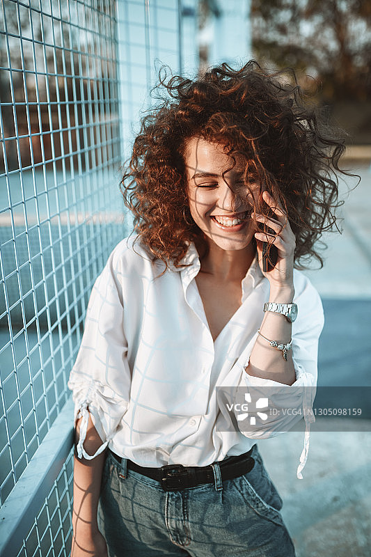 在网球场边放松时享受电话交谈的微笑女人图片素材