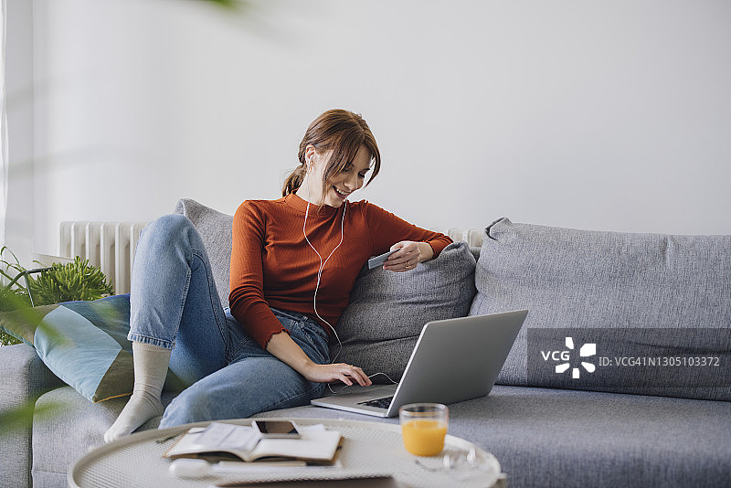 商界女性：使用笔记本电脑在家进行网上购物的微笑女商人图片素材