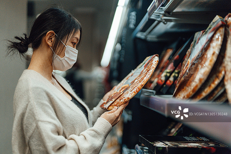 年轻女子在超市的冷藏架上取食物图片素材