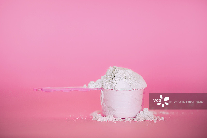 粉色背景下的量勺与胶原蛋白粉或乳清蛋白或海藻酸盐面膜 - 年度潮流产品图片素材