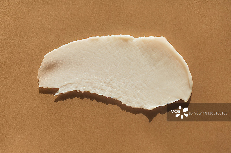 米色背景上的白色乳霜涂抹，年度潮流护肤图片素材