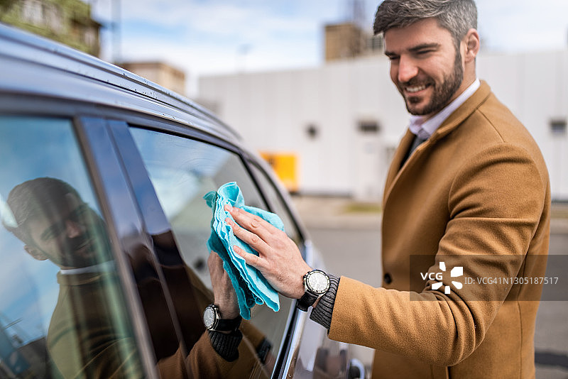 快乐的男人清洁汽车车窗图片素材