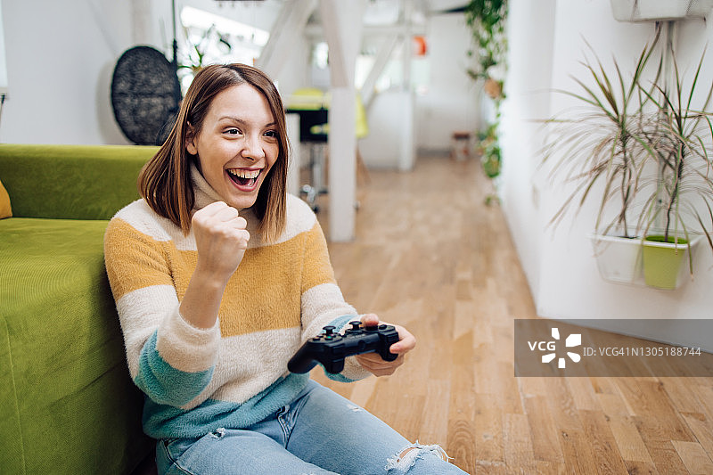 正在玩游戏并欢呼的开朗年轻女子肖像图片素材