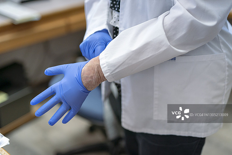 医疗专业人员戴上蓝色无菌外科手套图片素材
