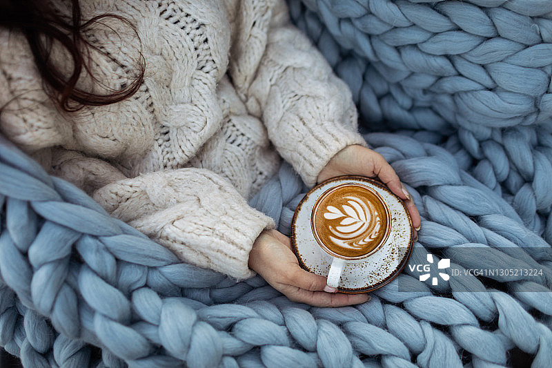 盖着毯子手持热咖啡杯的女人图片素材